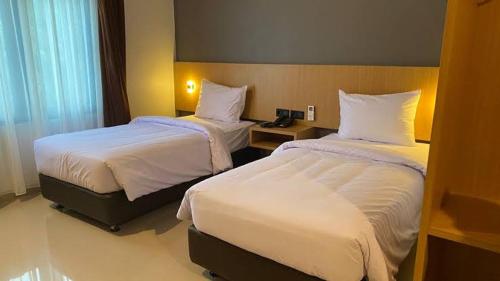 a hotel room with two beds with white sheets at Apartemen suhat in Malang