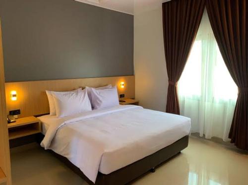 - une chambre avec un grand lit blanc et une fenêtre dans l'établissement Apartemen suhat, à Malang