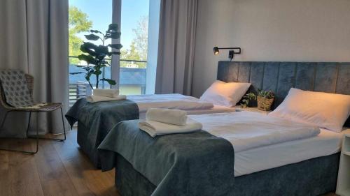 a bedroom with two beds and a large window at Wakacyjny apartament & SPA nad morzem in Dziwnów