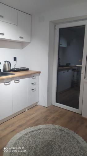 a kitchen with white cabinets and a large sliding glass door at Pokój typu studio nr 2 in Sromowce Wyżne