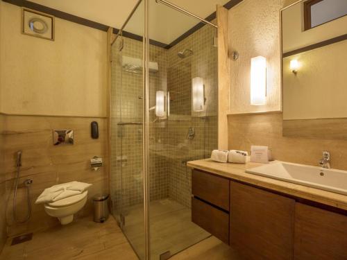W łazience znajduje się prysznic, toaleta i umywalka. w obiekcie Deltin Suites w mieście Candolim