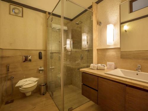 a bathroom with a shower and a toilet and a sink at Deltin Suites in Candolim