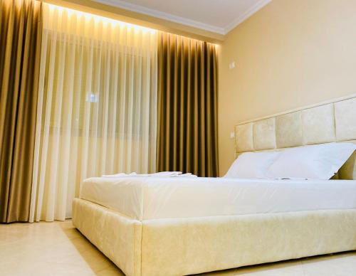 a bedroom with a large white bed and curtains at Holiday Apartment in Vlorë