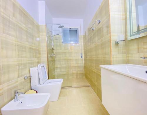 a bathroom with a toilet and a sink and a tub at Holiday Apartment in Vlorë