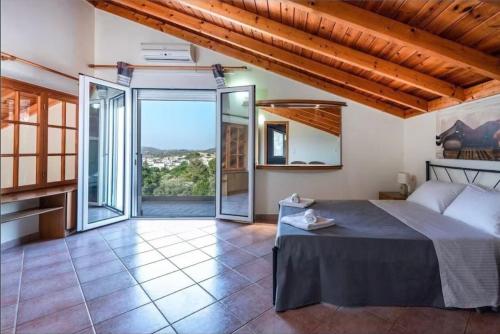 a bedroom with a bed and a large window at villa Aphrodite Maritsa in Pastida