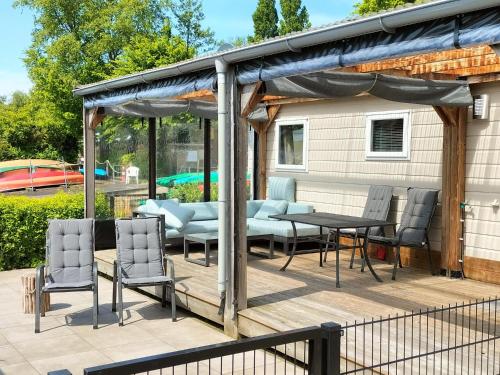 a pavilion with a table and chairs on a deck at Camping Kleine Belterwijde, Haven Chalet in Belt-Schutsloot