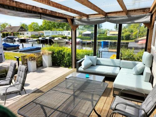 a patio with a couch and a table and chairs at Camping Kleine Belterwijde, Haven Chalet in Belt-Schutsloot