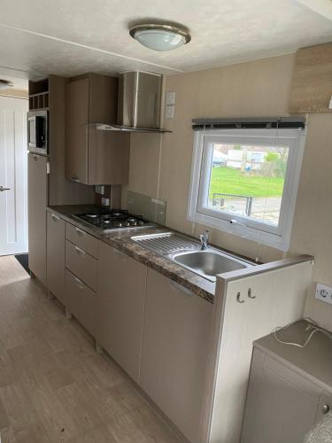 a small kitchen with a sink and a window at Camping Kleine Belterwijde, Haven Chalet in Belt-Schutsloot