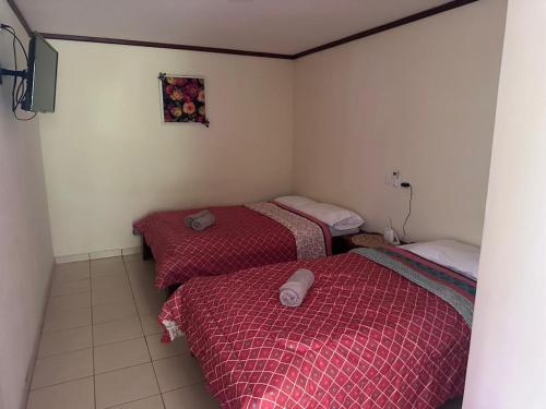 two beds in a small room with red sheets at RIVER SIDE LODGE in Horquetas