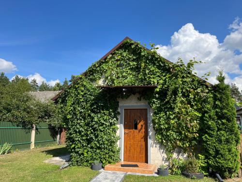 a small house covered in ivy with a door at Siedlisko pod Lasem in Józefów