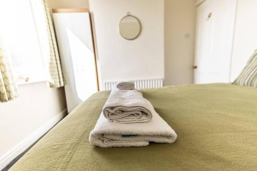 a stack of towels sitting on the end of a bed at Stunning Holiday Home - Puddleduck - Centre of Coniston in Coniston