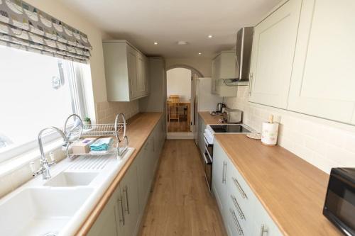 a kitchen with white cabinets and a sink and a window at Stunning Holiday Home - Puddleduck - Centre of Coniston in Coniston