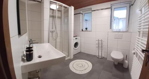 een witte badkamer met een wastafel en een wasmachine bij Ferienwohnung Wenzl in Schnaitsee