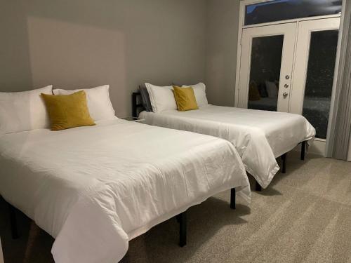 Duas camas com lençóis brancos e almofadas amarelas num quarto em 2 bedroom 4 beds Apartment on the heart of Legacy West em Plano