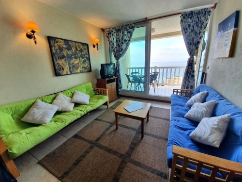 sala de estar con sofá verde y balcón en Oceana Suites Bahia Pelicanos en Puchuncaví