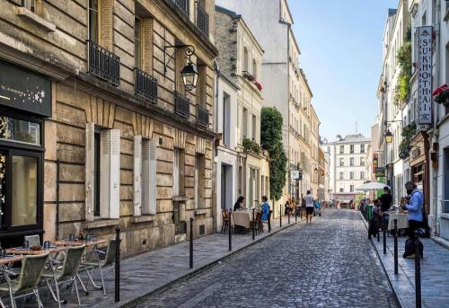 una calle adoquinada en una ciudad con mesas y sillas en Charming parisian apartment, en París