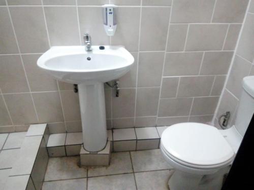 a bathroom with a white sink and a toilet at MEDUPI 2 Guesthouse. in Kempton Park