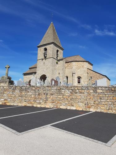 a building with a stone wall and a church at les abeilles du cantou in Termes