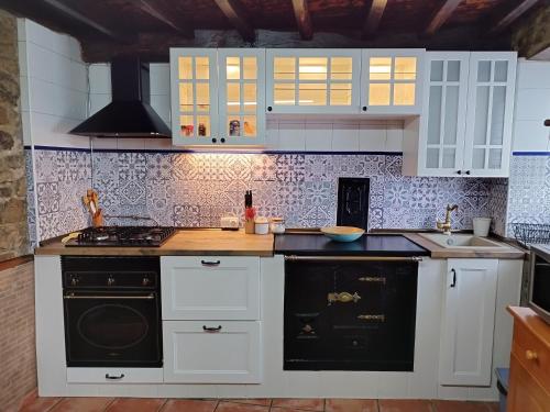 a kitchen with white cabinets and black appliances at Casa Rural El Corquieu de la Cava in San Feliz