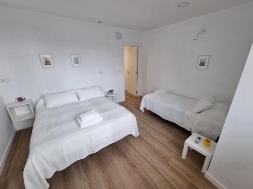 a white bedroom with two beds and a couch at Apartamentos y estudios EL CENTRO in Vargas
