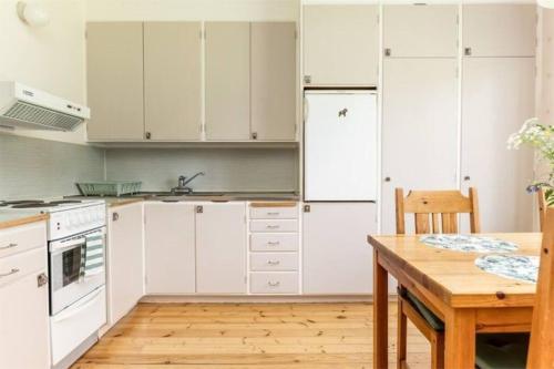a kitchen with white cabinets and a wooden table at Appartement in de natuur! in Fredriksberg