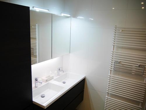een witte badkamer met een wastafel en een spiegel bij Residentie Sweetnest met hotelservice à la carte in Knokke-Heist