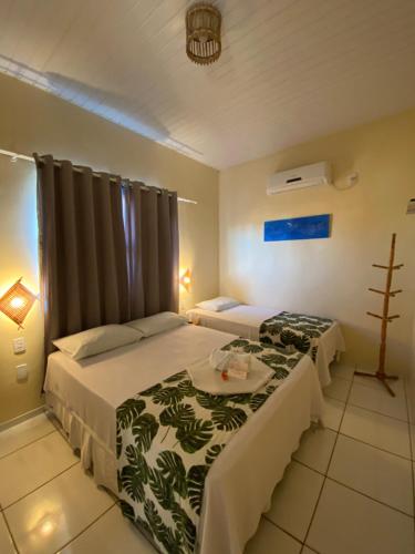 a hotel room with two beds and a table at Pousada Do Porto in Barreirinhas