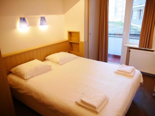 1 dormitorio con 1 cama blanca y 2 toallas en Residentie Sweetnest met hotelservice à la carte en Knokke-Heist