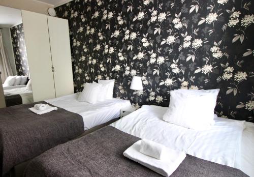 2 camas en una habitación de hotel con papel pintado floral en Orchidea Kamppi, en Helsinki