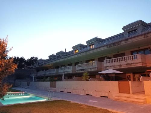 un hotel con piscina frente a un edificio en ATICO A 3 KM DE SANXENXO CON PISCINA Y GARAJE en Sanxenxo