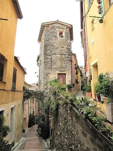 un antiguo edificio de piedra en un callejón con plantas en VieuxChateau, en Menton