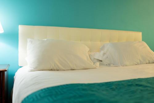 a bed with white pillows and a blue wall at Howard Johnson by Wyndham Niagara Falls in Niagara Falls