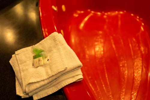 a red chair with a white towel with a house on it at Howard Johnson by Wyndham Niagara Falls in Niagara Falls