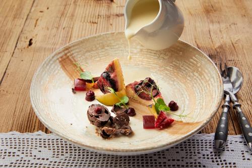a plate of food with fruit and a cup of milk at Gramai Alm alpengenuss & natur spa in Pertisau