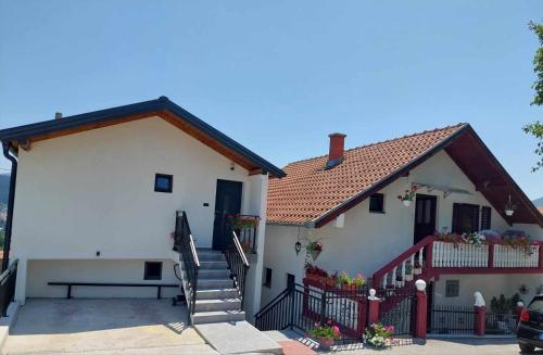 Uma casa branca com um banco à frente. em Guesthouse Jelena em Višegrad