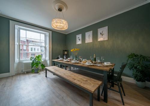 uma sala de jantar com uma mesa e um banco em Clifton Town House with Cinema Room Perfect for Groups, Families, Friends Hens & Stags! em Bristol