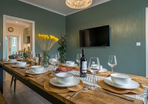a wooden table with plates and wine glasses on it at Premium Designer 4 Bedroom Home in Clifton - 3 Bathrooms & Cinema Room in Bristol
