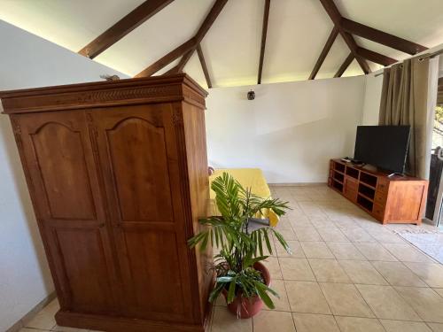 uma sala de estar com um armário de madeira e uma planta em O'coco Bungalow em Paea