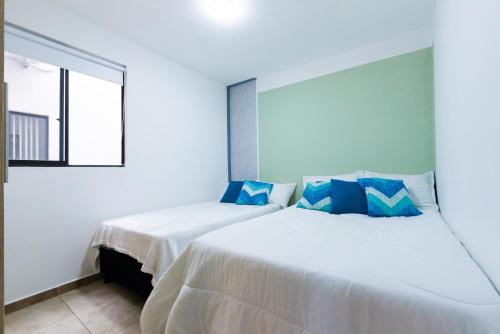- une chambre blanche avec 2 lits et des oreillers bleus dans l'établissement Hábitat Blue Sky La Tebaida, à La Tebaida