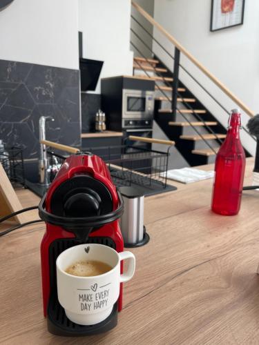 a red coffee maker sitting on a table with a cup of coffee at Résidence Tamaris Loft House in La Mézière