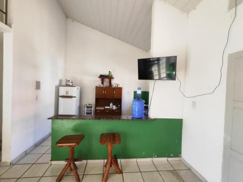 a kitchen with a green counter and two stools at Barreirinhas - Chalé Tubarão in Barreirinhas