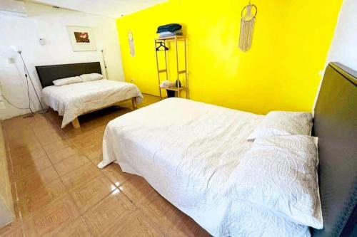 ein Schlafzimmer mit 2 Betten und einer gelben Wand in der Unterkunft Magical views of the Sea of Cortez with BBQ & Wi-fi in Rancho El Pozo