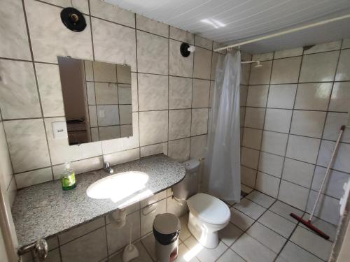 a bathroom with a sink and a toilet and a mirror at Barreirinhas - Chalé Tubarão in Barreirinhas
