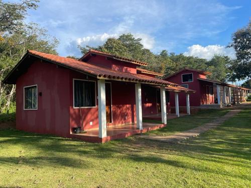 a red house with a porch in the grass at Chalés do Recanto in São João del Rei