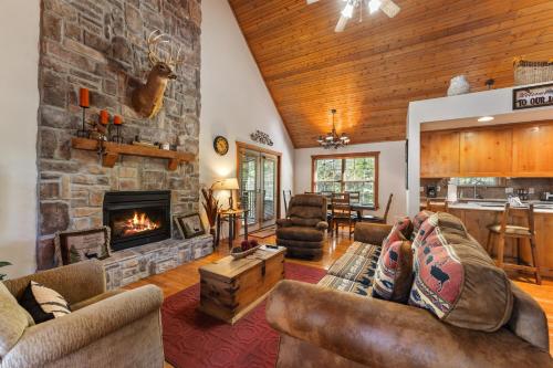 sala de estar con chimenea y pared de piedra en Whispering Woods Lodge Home, en Branson West