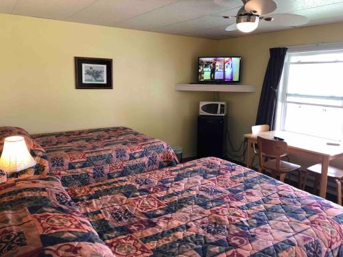 a hotel room with a bed and a table and a window at Lakelawn B&B and Motel in Yarmouth