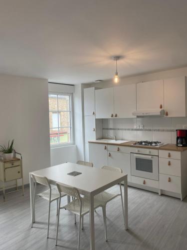 une cuisine avec une table et des chaises dans une pièce dans l'établissement Résidence de la poste, à Saint-Pol-de-Léon