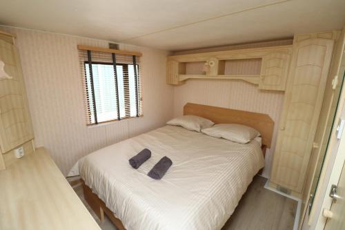 a bedroom with a bed with two shoes on it at De Zuidvliet Chalet 3 in Wolphaartsdijk