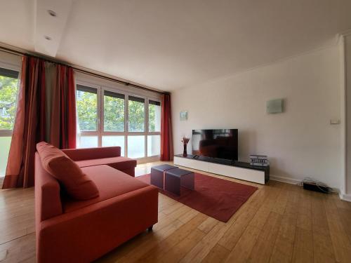 ein Wohnzimmer mit einem roten Sofa und einem Flachbild-TV in der Unterkunft Spacious Apartment near Paris, for Family and Friends in Montrouge