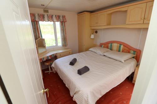 1 dormitorio pequeño con 1 cama con 2 zapatillas en De Zuidvliet Chalet 4, en Wolphaartsdijk